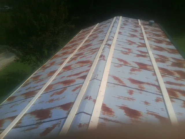 Rusted metal roof panels with new wood purlins before replacement — Storm Damage Roof Repair in Marquette by Roofing Brothers