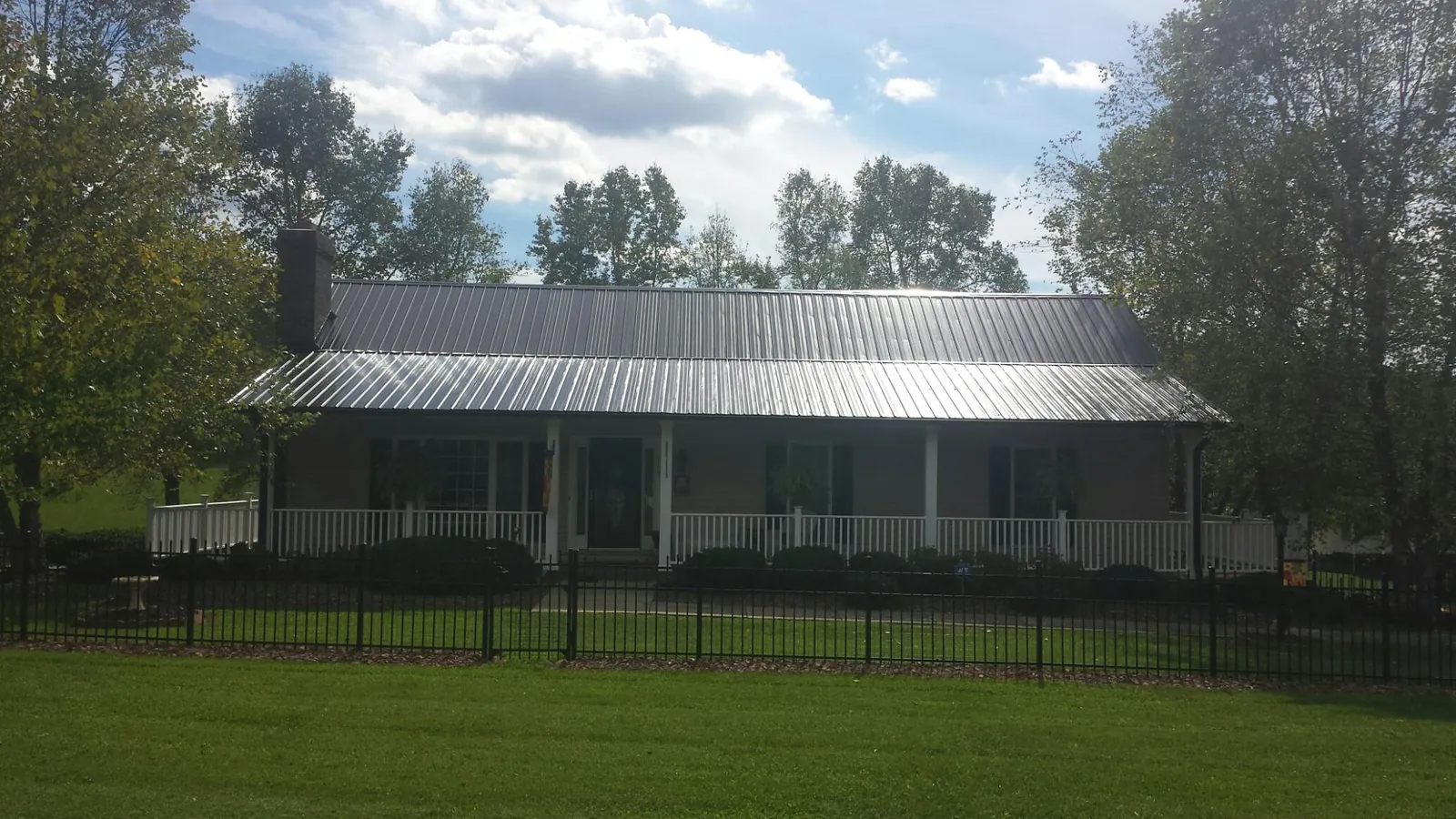 Gray metal roof on a brick ranch with a full width front porch — Gutter Guard Installation work by our crew in Marquette