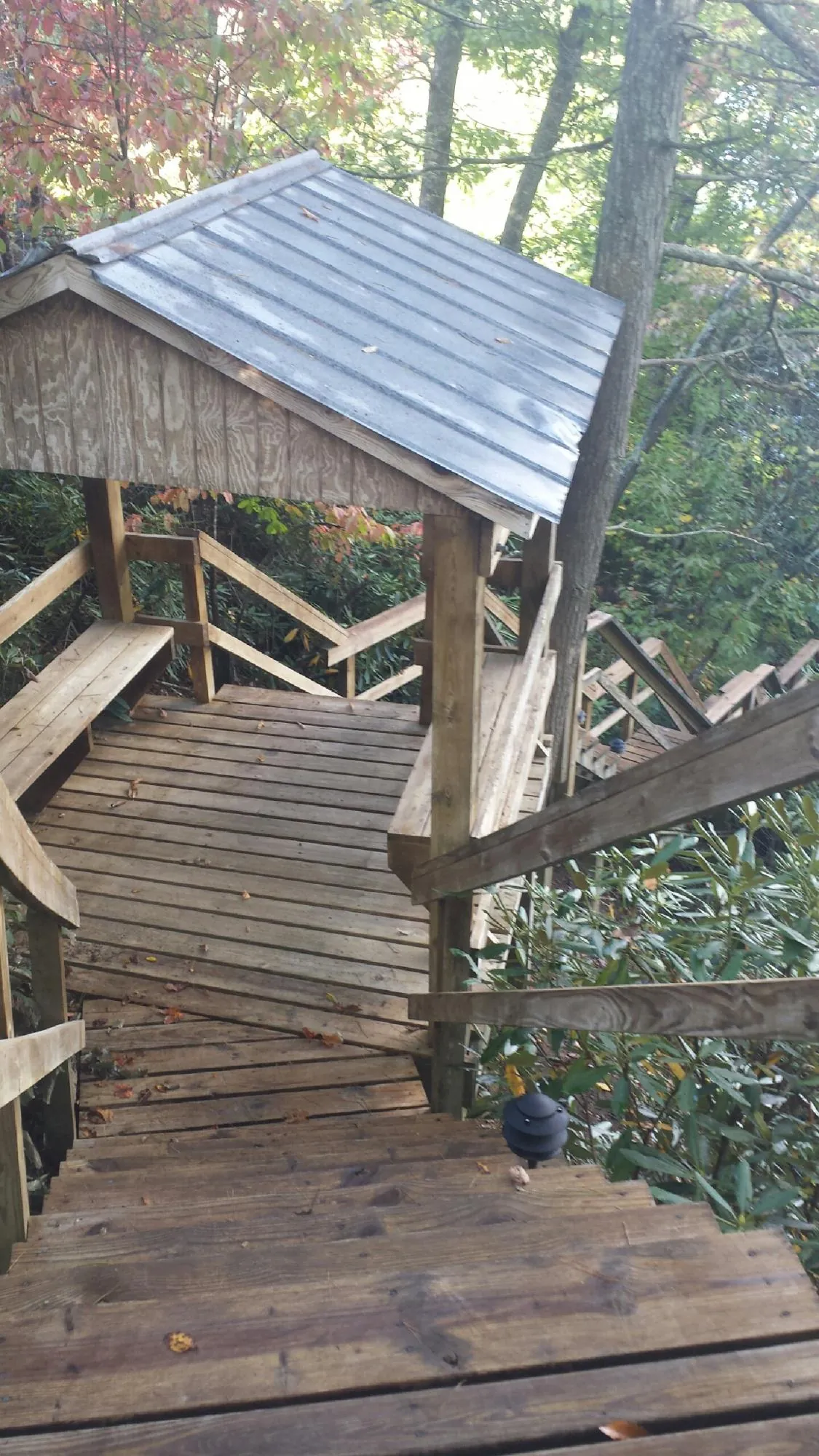 Metal roofed shelter over wooden steps on a wooded walkway — Skylight Repair & Installation work by our crew in Marquette