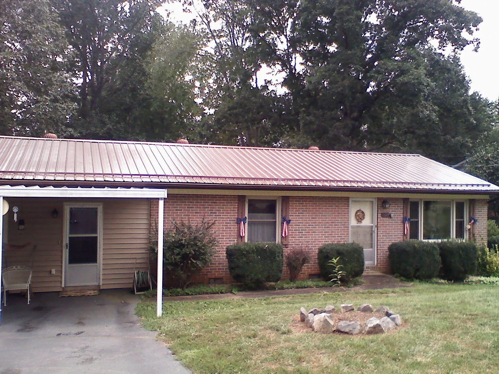 Bronze metal roof and carport on a brick ranch home — Roof Repair work by our crew in Marquette